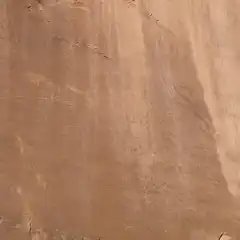 A large expanse of light brown rock with faint petroglyphs.