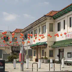 A street lined with buildings featuring Asian-style architecture and red lanterns hanging above.