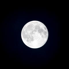 A full moon shining brightly against a dark night sky.