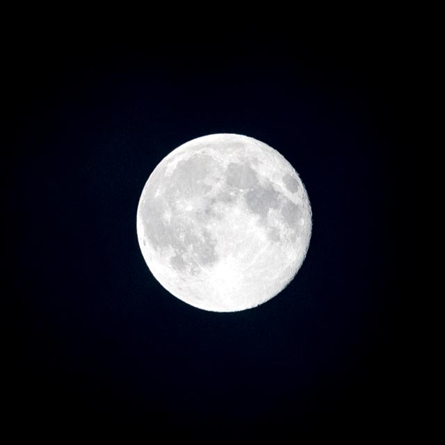 A full moon shining brightly against a dark night sky.