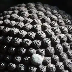 A textured surface composed of tightly packed, spiral-shaped elements arranged in a grid pattern.