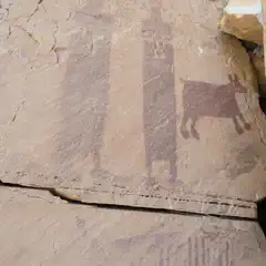 A large rock formation is visible, featuring a painting of an animal and human figures.