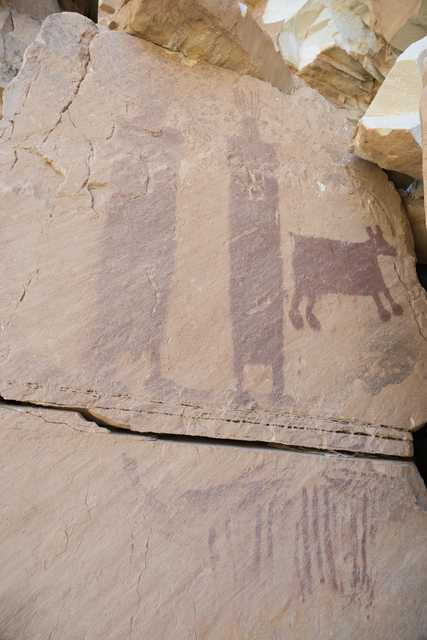 A large rock formation is visible, featuring a painting of an animal and human figures.