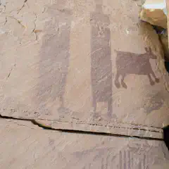 A large rock formation is visible, featuring a painting of an animal and human figures.