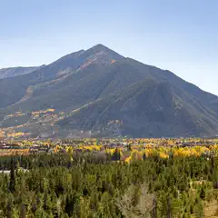 A mountainous landscape with a town at its base and trees turning yellow in autumn.