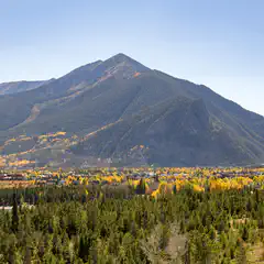 A mountainous landscape with a town at its base and trees turning yellow in autumn.