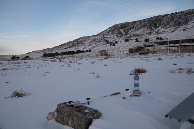 A small, makeshift grave marker set into snow-covered ground against a backdrop of barren trees and distant mountains.