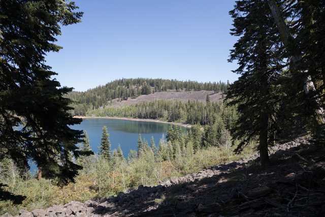 A lake surrounded by evergreen trees and rocky terrain.