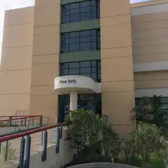 A multi-story building has a green section on the upper level and a white entryway with a curved sign above the doors.