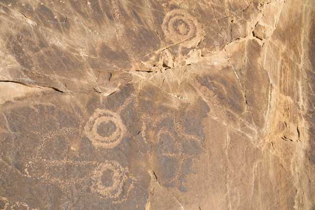 A rock with petroglyphs of concentric circles and other abstract designs carved into its surface.