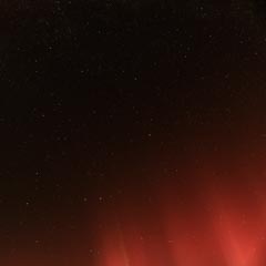 A night sky filled with stars and red aurora.
