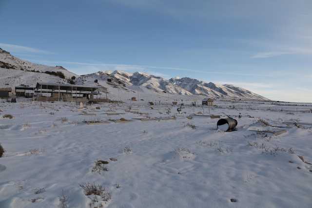 A snowy landscape with mountains in the background and small gravesites covered in snow.