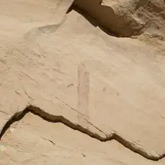 A rock formation features a faint red drawing that appears to depict a human figure.
