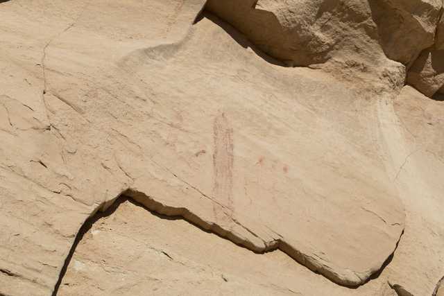 A rock formation features a faint red drawing that appears to depict a human figure.