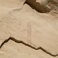 A rock formation features a faint red drawing that appears to depict a human figure.