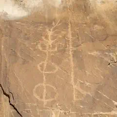 An abstract petroglyph is etched into a rock face.