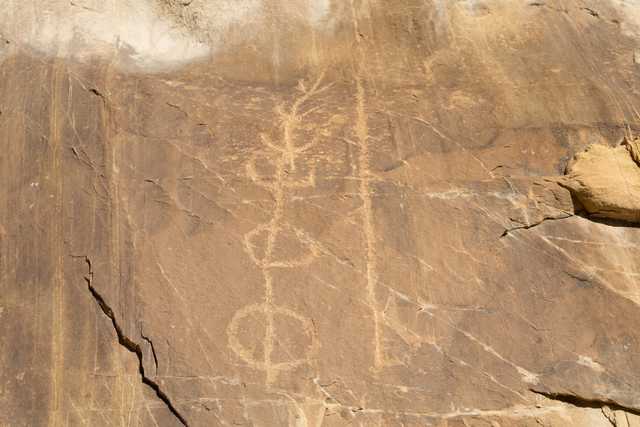 An abstract petroglyph is etched into a rock face.