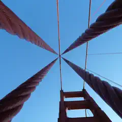 A close-up view of a bridge's suspension cables against a clear blue sky.