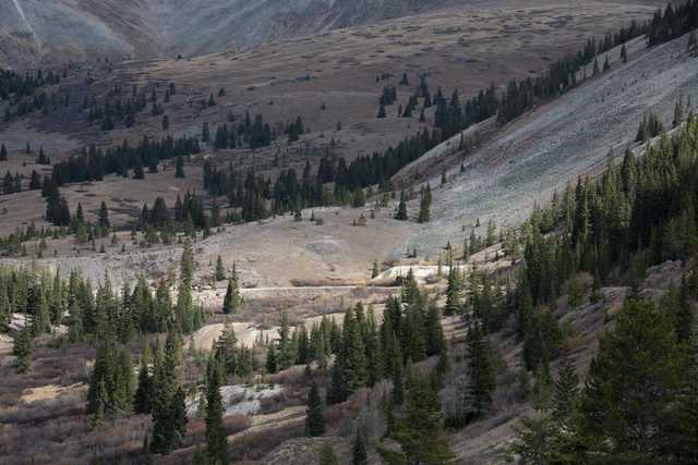 An abandoned mine site is visible in the background, surrounded by a landscape dotted with trees.