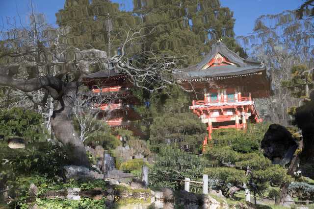 An ornate red pagoda stands among trees and greenery, with multiple levels featuring windows and railings.