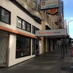 A sign for a hostel on a building with a brick facade and windows.