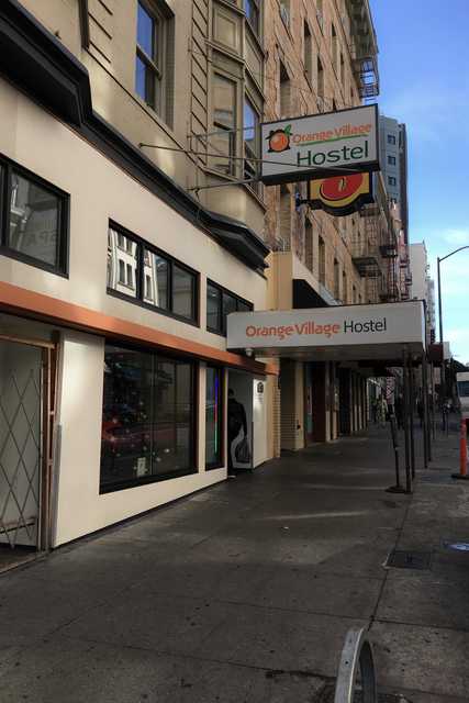 A sign for a hostel on a building with a brick facade and windows.