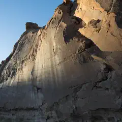 A rocky mountain ridge at sunset, with sunlight casting shadows on the rock surfaces.