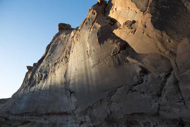 A rocky mountain ridge at sunset, with sunlight casting shadows on the rock surfaces.
