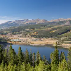 A mountain lake with a town and mountains in the background.
