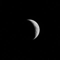 A crescent moon against a dark night sky.