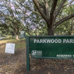 A green sign in front of a tree reads 'Parkwood Park'.