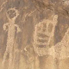 A rock surface with petroglyphs of a human figure and various other shapes.