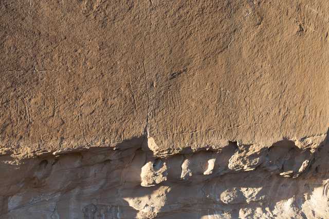 A large section of sandstone rock is visible, characterized by its rough texture and numerous scratches.