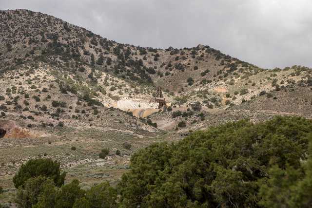 A rugged hillside with sparse vegetation and a small open-pit mine.