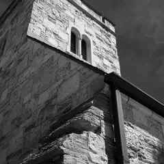 A stone tower rises against a dark sky, and a drainpipe runs vertically along its surface.