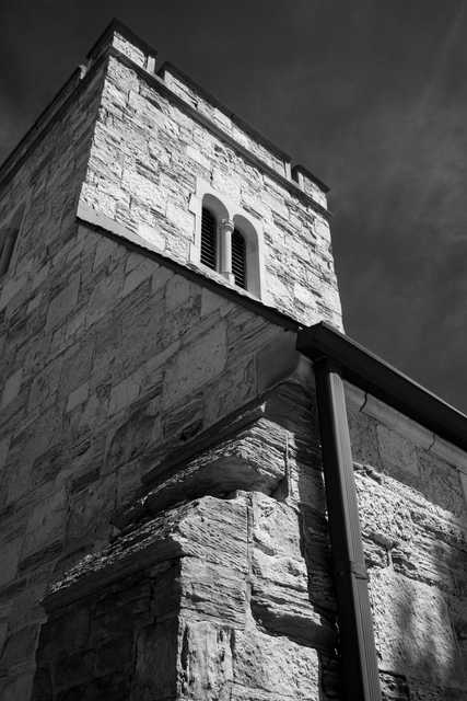 A stone tower rises against a dark sky, and a drainpipe runs vertically along its surface.