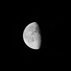 A portion of the moon's surface, showing several craters and a prominent crater near the right edge.
