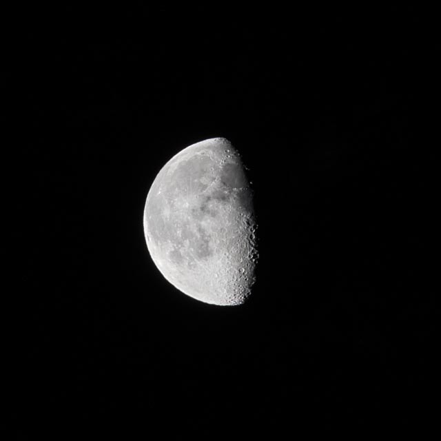A portion of the moon's surface, showing several craters and a prominent crater near the right edge.