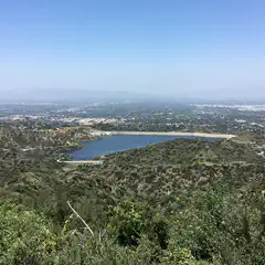 An artificial lake is surrounded by hills covered in greenery.