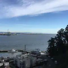 A harbor with a dock and boats on calm water under a partly cloudy sky, with buildings lining the shore.
