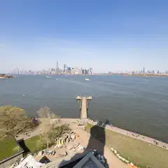 A large body of water with boats and a city skyline in the distance, viewed from an elevated perspective on a clear day.
