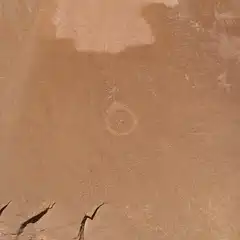 A reddish-orange cliff face features a prominent circular marking in its center.