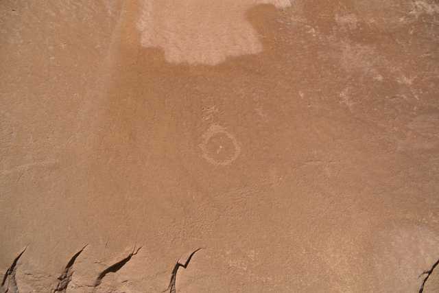 A reddish-orange cliff face features a prominent circular marking in its center.