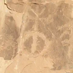 A rock surface with a circular petroglyph and other indistinct markings.