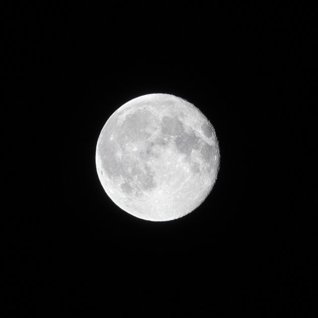 An almost full moon is seen against a black background.