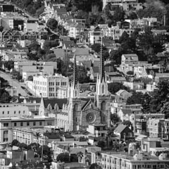 A Gothic-style church with tall spires and a large rose window is surrounded by residential buildings.