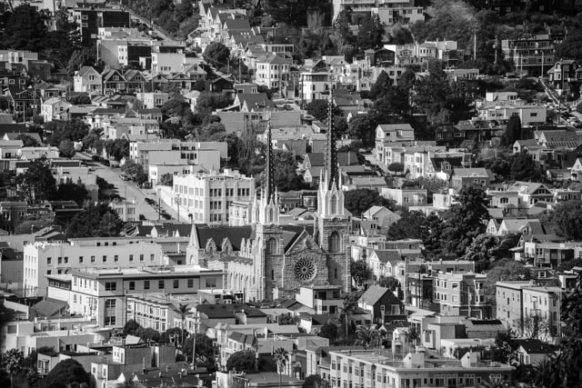 A Gothic-style church with tall spires and a large rose window is surrounded by residential buildings.