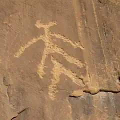 An abstract figure with outstretched arms is carved into a rock surface.