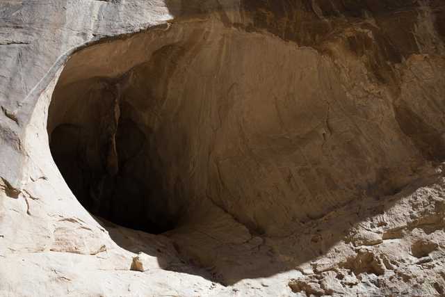 A large hole in a rock face is visible, surrounded by tan and brown stone.