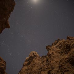 A night sky filled with stars visible through a natural rock formation.